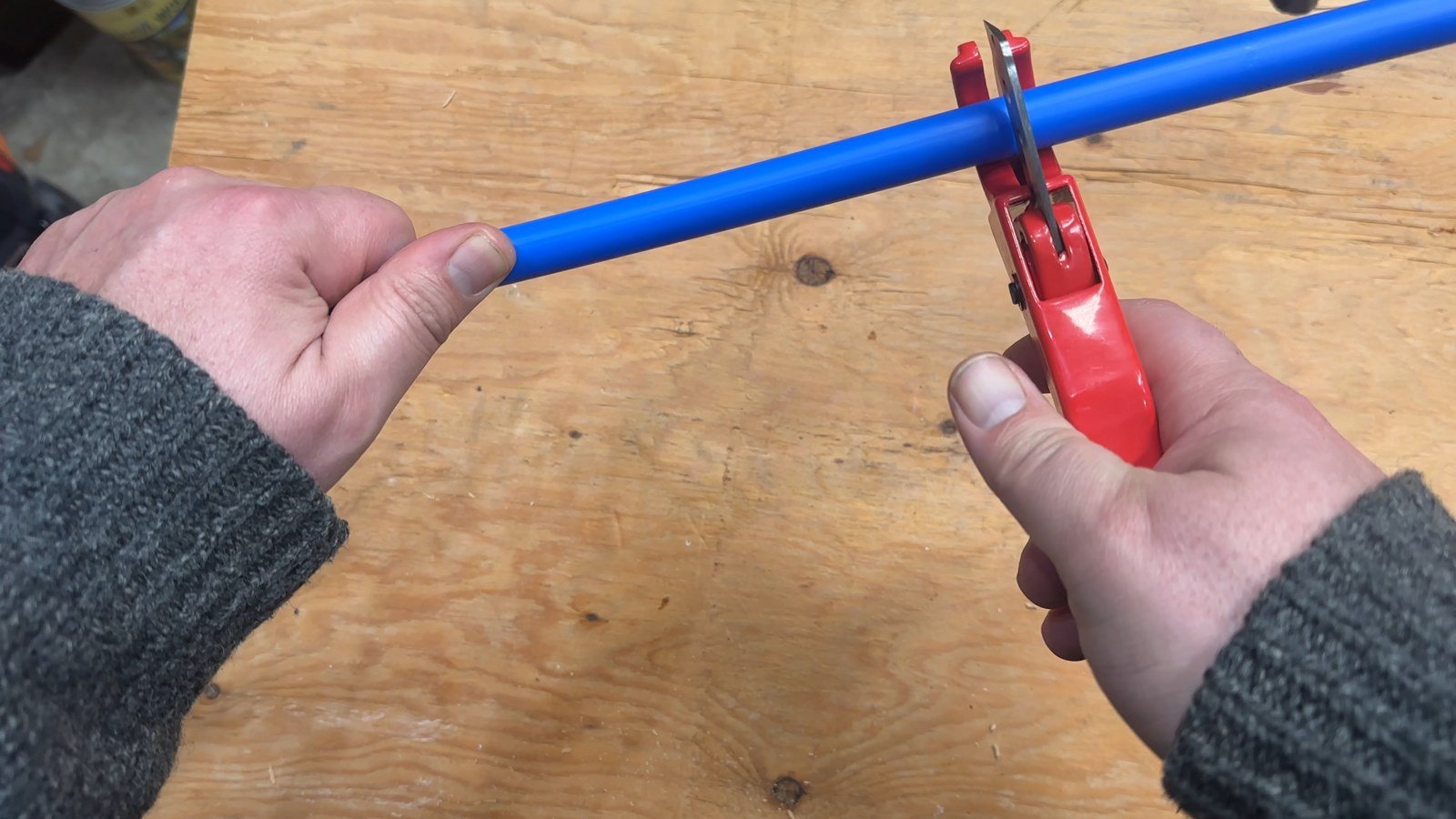 Cutting blue half-inch PEX tubing with the included pipe cutter