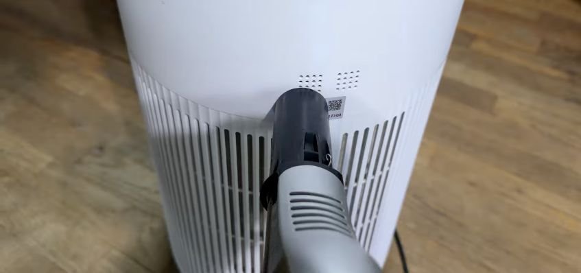 Vacuum nozzle cleaning the small dust-sensor openings on the back of a Shark air purifier.