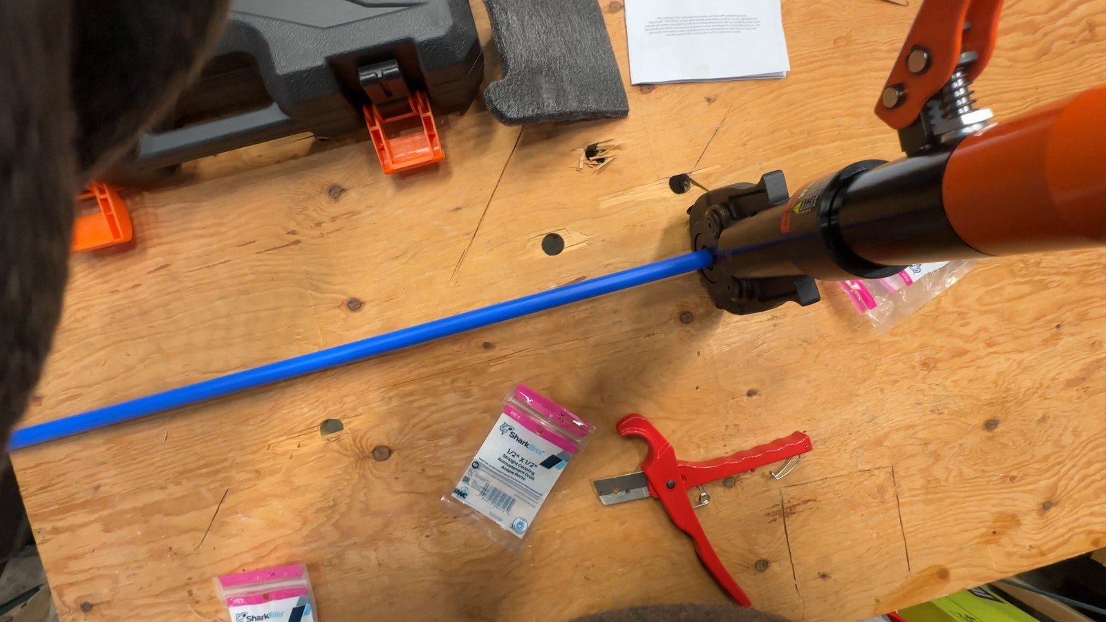 The VEVOR hydraulic tool positioned around a copper crimp ring on blue PEX tubing